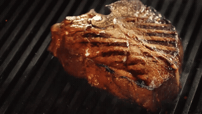A Steak Is Cooking On A Grill With A Lot Of Smoke Coming Out Of It GIF