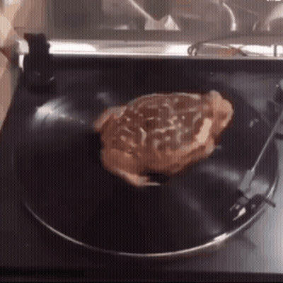 A Steak Is Sitting On A Record On A Record Player GIF