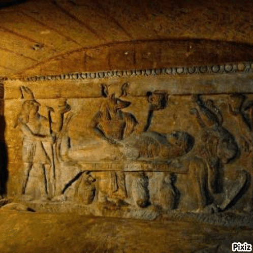 A Stone Carving Of A Man Laying On A Bed In A Cave Surrounded By Animals . GIF