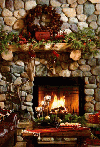 A Stone Fireplace Decorated For Christmas With A Wreath And Stockings On The Mantle GIF