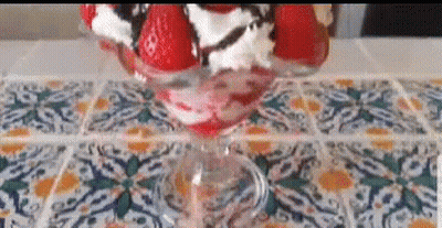 A Strawberry Sundae With Whipped Cream And Chocolate Sauce In A Glass On A Table . GIF