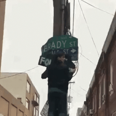 A Street Sign For Brady St. Is Hanging From A Pole GIF