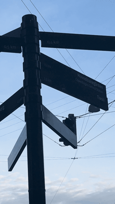 A Street Sign Shows The Distance To Various Locations Including Tivoli GIF