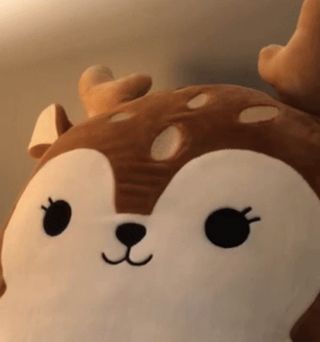 A Stuffed Animal In The Shape Of A Deer With A Black Nose And Eyes GIF