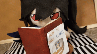A Stuffed Animal Is Reading A Book About How To Bake A Cake GIF
