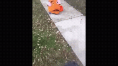 A Stuffed Animal Is Sitting On The Sidewalk Next To A Person 'S Foot . GIF