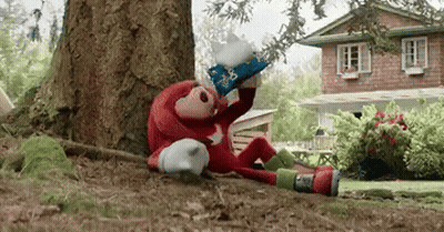 A Stuffed Animal Is Sitting Under A Tree In Front Of A House Wearing A Wizard 'S Hat . GIF