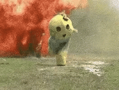 A Stuffed Animal Is Standing In The Grass With Smoke Coming Out Of It 'S Mouth . GIF