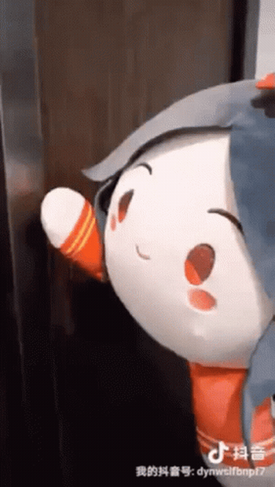 A Stuffed Animal Is Standing Next To A Door And Waving At It . GIF