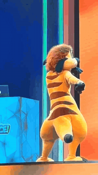 A Stuffed Animal Is Standing On A Stage In Front Of A Microphone . GIF