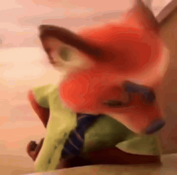 A Stuffed Animal Of A Fox Wearing A Green Shirt And Tie Is Sitting On A Bed . GIF