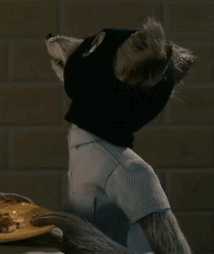 A Stuffed Animal With A Cat 'S Head Is Sitting In Front Of A Plate Of Food GIF