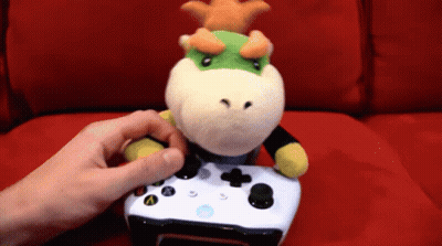 A Stuffed Animal With A Crown On Its Head Is Sitting On A Xbox Controller GIF