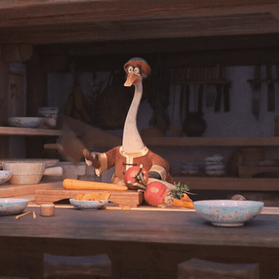 A Stuffed Animal With A Long Neck Is Sitting On A Counter With Vegetables GIF