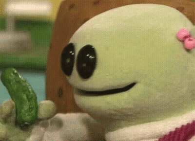 A Stuffed Animal With A Pink Bow On Its Head Is Holding A Green Pickle . GIF