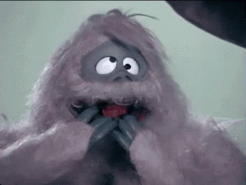 A Stuffed Animal With Big Eyes And A Red Tongue Is Eating A Red Apple . GIF