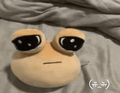 A Stuffed Animal With Big Eyes Is Laying On A Bed With A Smiley Face On It . GIF