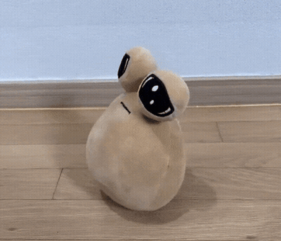 A Stuffed Animal With Big Eyes Is Sitting On A Hardwood Floor GIF