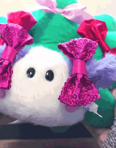 A Stuffed Animal With Pink Bows On Its Ears GIF