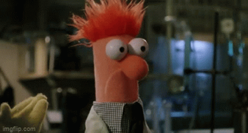 A Stuffed Animal With Red Hair And Big Eyes Is Wearing A Lab Coat And A Tie . GIF