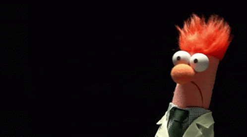 A Stuffed Animal With Red Hair And Big Eyes Is Wearing A Lab Coat And Tie GIF
