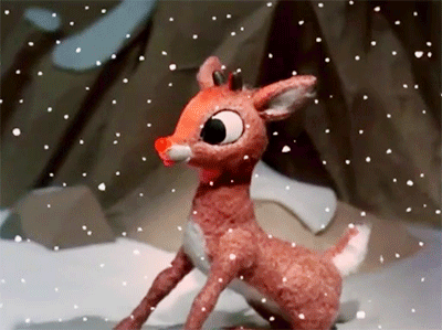 A Stuffed Deer With A Red Nose Is Standing In The Snow GIF