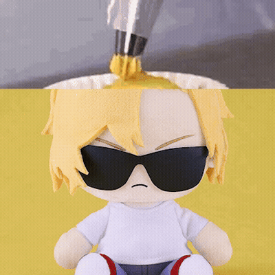 a stuffed doll wearing sunglasses is sitting on a yellow table