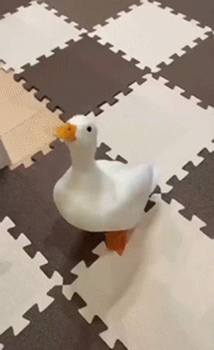 A Stuffed Duck With A Yellow Beak Is Walking On A Puzzle Mat GIF
