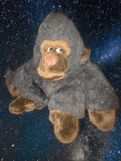 A Stuffed Gorilla Is Floating In The Air With A Starry Sky In The Background GIF