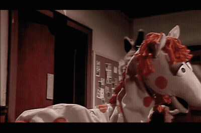 A Stuffed Horse With A Red Mane And Tail Is Standing In A Hallway GIF