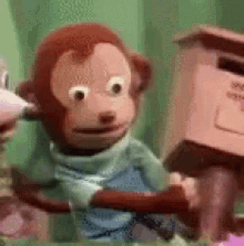 A Stuffed Monkey Is Sitting On A Tree Branch Next To A Pink Mailbox . GIF