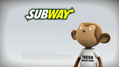 A Stuffed Monkey Is Standing In Front Of A Subway Ad GIF