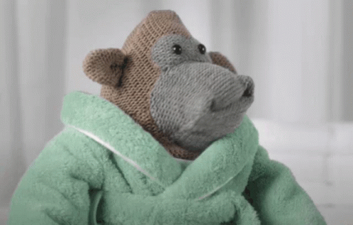 A Stuffed Monkey Wearing A Green Towel Around His Neck GIF
