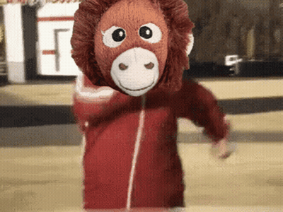 A Stuffed Monkey Wearing A Red Jacket And A Mask GIF