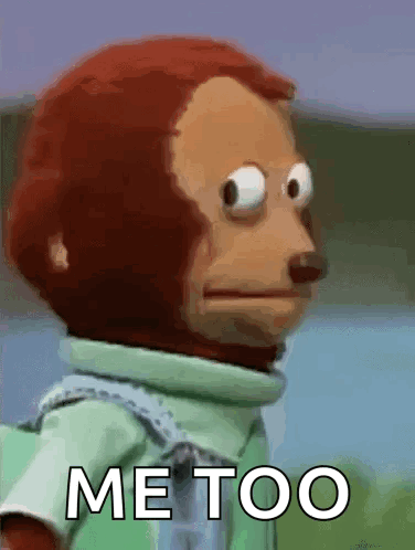 A Stuffed Monkey With Big Eyes Is Standing In Front Of A Sign That Says Me Too . GIF