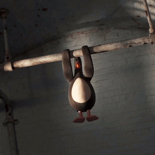 A Stuffed Penguin Is Hanging From A Pipe In A Dark Room GIF