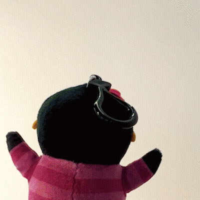 A Stuffed Penguin Wearing A Pink And Black Striped Sweater With A Keychain Attached To It GIF