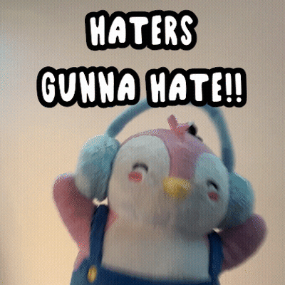 A Stuffed Penguin Wearing Ear Muffs And Overalls Says Haters Gunna Hate GIF