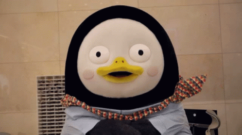 A Stuffed Penguin With A Yellow Beak Is Holding A Cat GIF