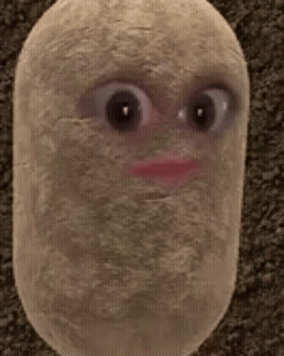 A Stuffed Potato With Big Eyes And A Red Lip Is Sitting On A Carpet . GIF