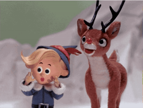 A Stuffed Reindeer Standing Next To A Cartoon Character GIF