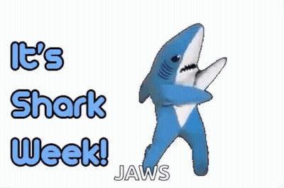 A Stuffed Shark Is Dancing In Front Of A Sign That Says `` It 'S Shark Week ! Jaws '' . GIF