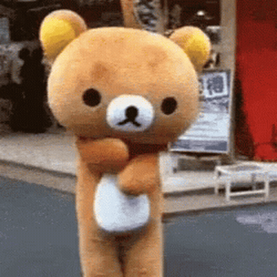 A Stuffed Teddy Bear Is Standing In Front Of A Store GIF