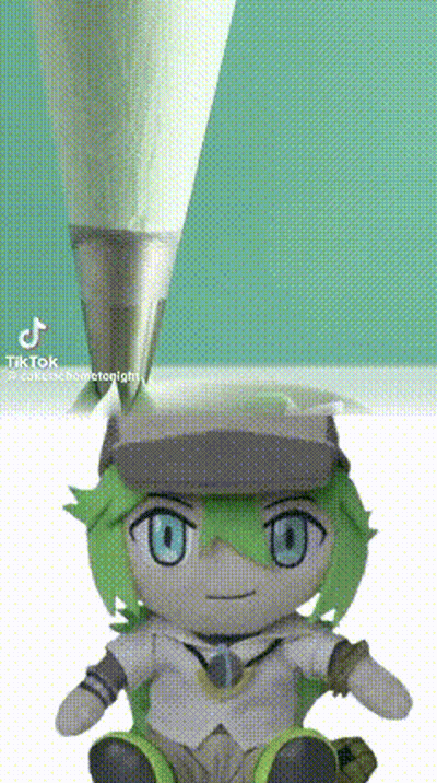 A Stuffed Toy With Green Hair And Blue Eyes Is Sitting Next To A Pencil . GIF