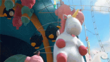 A Stuffed Unicorn Is Sitting On Top Of A Carnival Ride . GIF