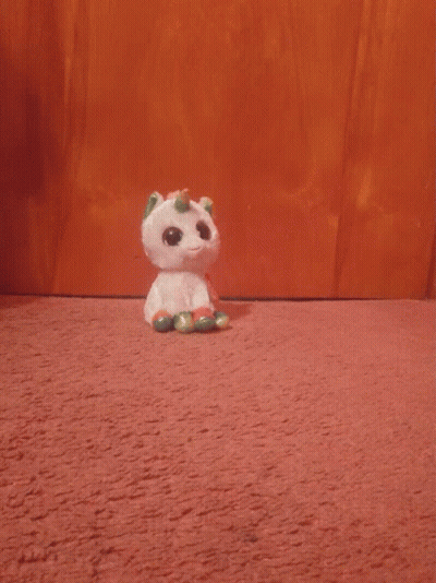 A Stuffed Unicorn With A Rainbow Horn Is Looking At The Camera GIF