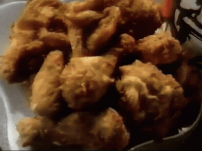 A Styrofoam Container Filled With Fried Chicken Pieces GIF
