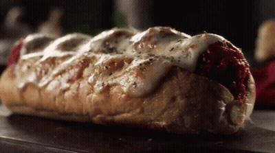 A Sub Sandwich With Meatballs And Cheese On A Table GIF