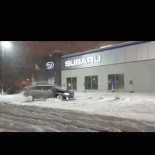 A Subaru Store With A Car In The Snow GIF