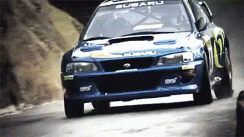 A Subaru Wrx Sti Is Driving Down A Hill . GIF